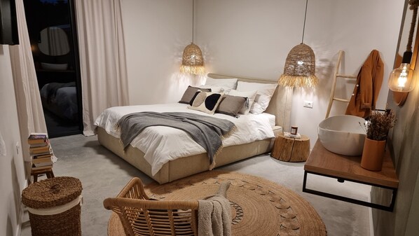 Une chambre à coucher comprenant un lit, des lampes de chevet, une table de chevet, une chaise, une petite table et un miroir.