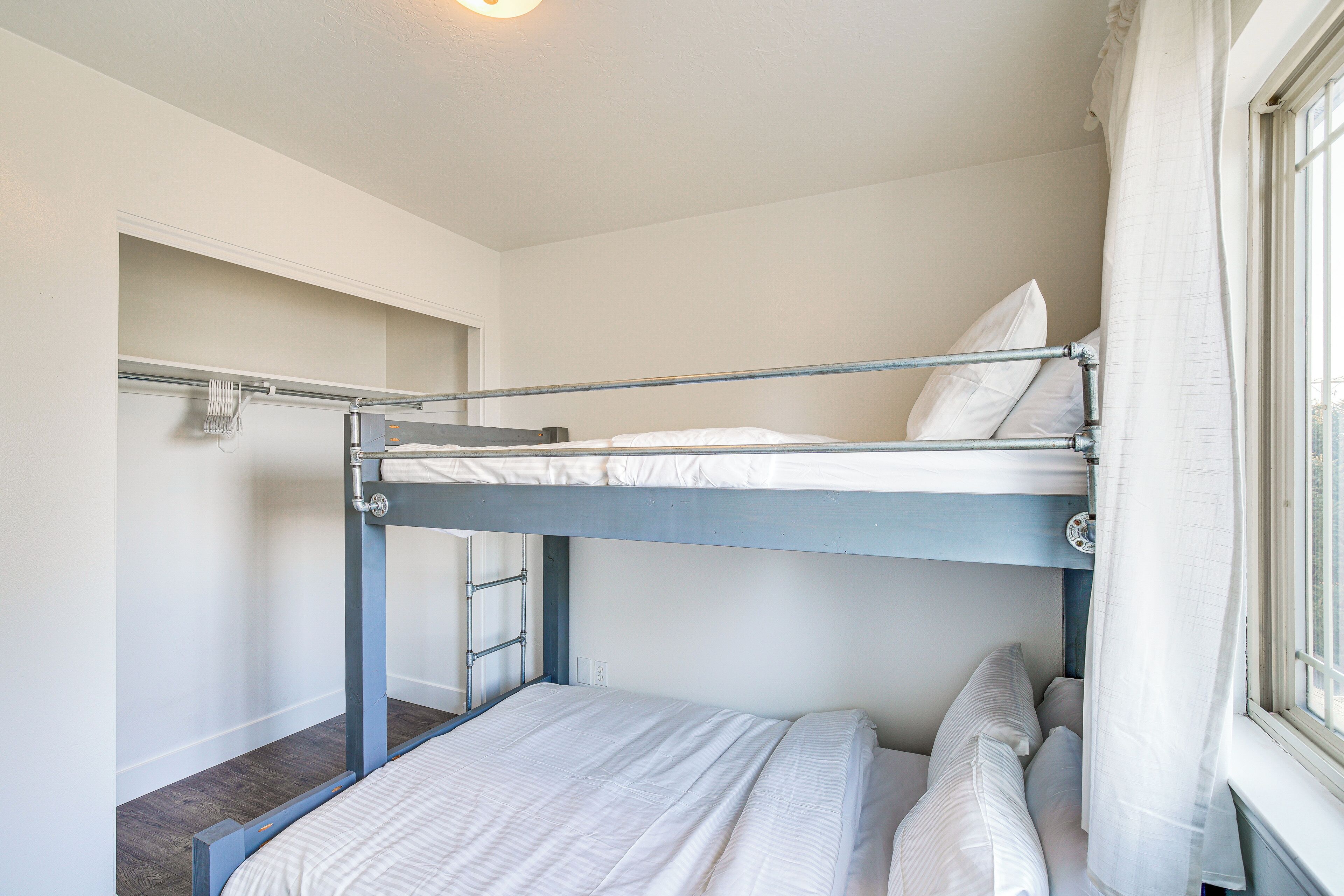 A bunk bed room with a window, a door, and a light fixture.