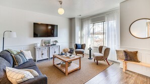 A living room with a sofa, a coffee table, a TV, and a window with curtains.