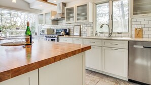 A modern kitchen with white cabinets, a wooden countertop, stainless steel appliances, and large windows. - Peaceful Lake George Getaway - 3 Mi to Beach! (Lake George)