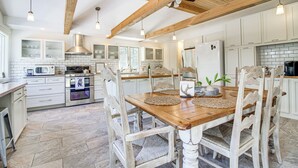 A spacious kitchen with white cabinetry, a wooden dining table, and a high ceiling with exposed beams. - Peaceful Lake George Getaway - 3 Mi to Beach! (Lake George)