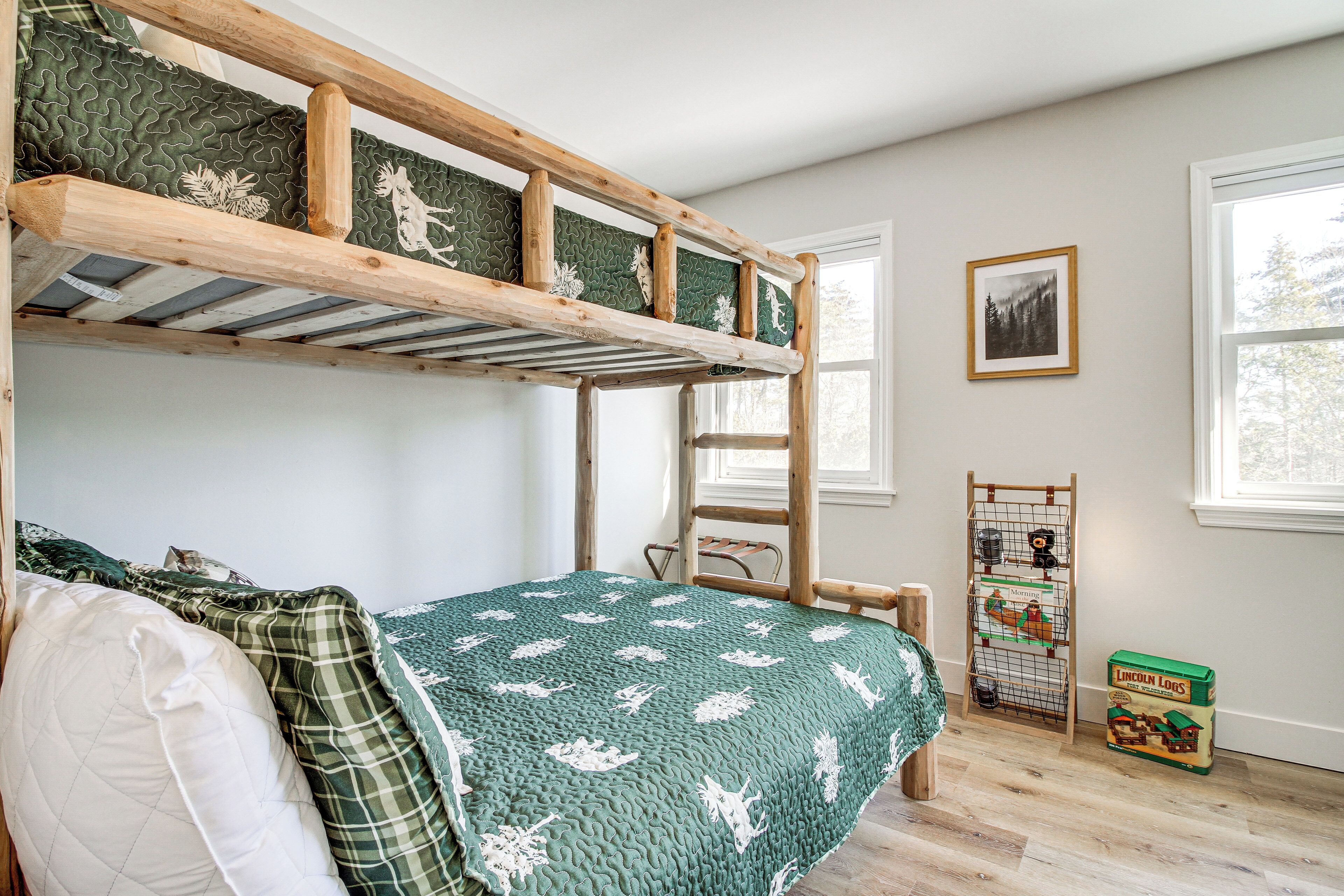 A bunk bed with a green quilt, a ladder, and a Lincoln Logs toy box.
