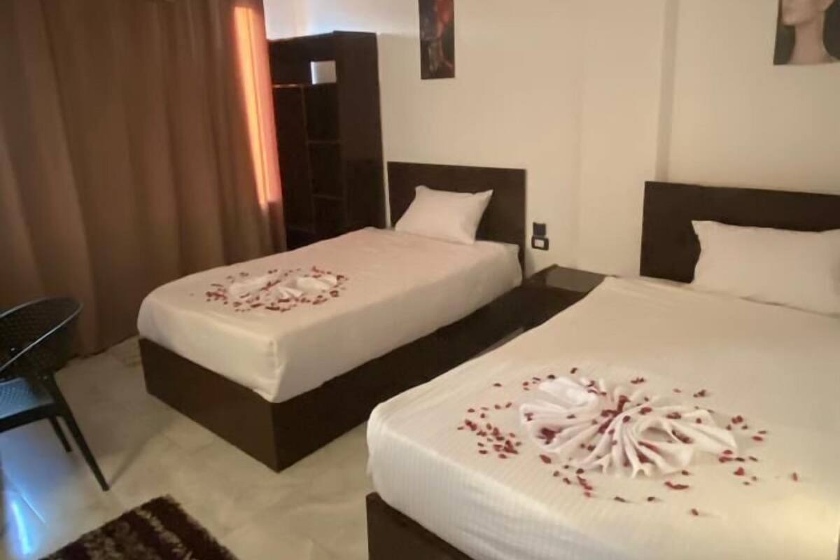 A hotel room with two beds, a desk, and a chair.