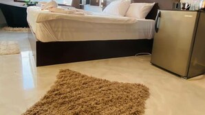 A modern hotel room with a bed, a small refrigerator, a large window with a view, and a fluffy rug. - VIP Al Fouad pyramids & spa (Giza)
