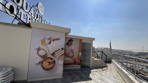 A rooftop area with a sign reading "LOUQUETTA HOTEL," a large poster advertising spa services, and a view of the cityscape. - VIP Al Fouad pyramids & spa (Giza)
