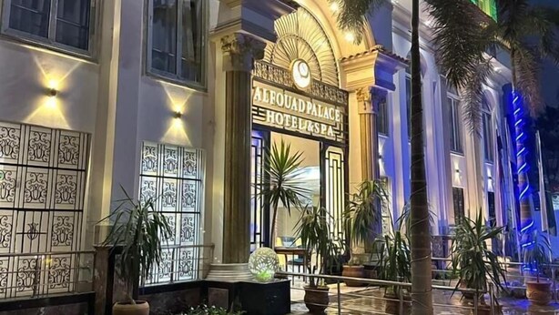 A hotel entrance with a sign reading "Alfouad Palace Hotel & Spa," featuring a grand archway, decorative wall panels, and a well-lit pathway with potted plants. - VIP Al Fouad pyramids & spa (Giza)