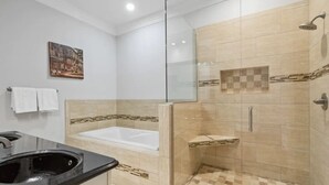 Un baño moderno con ducha de vidrio, bañera y tocador con lavamanos.