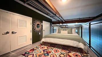 A bedroom with a bed, a patterned rug, a decorative wall piece, and a window with a view.