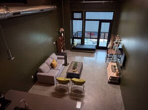 A modern living room with a sofa, coffee table, and chairs, a dining area with a table and chairs, and a large window with a view. - ⁂Pet Friendly⁂10min-Airport⁂AC⁂Gym⁂2Bed (Santa Ana)