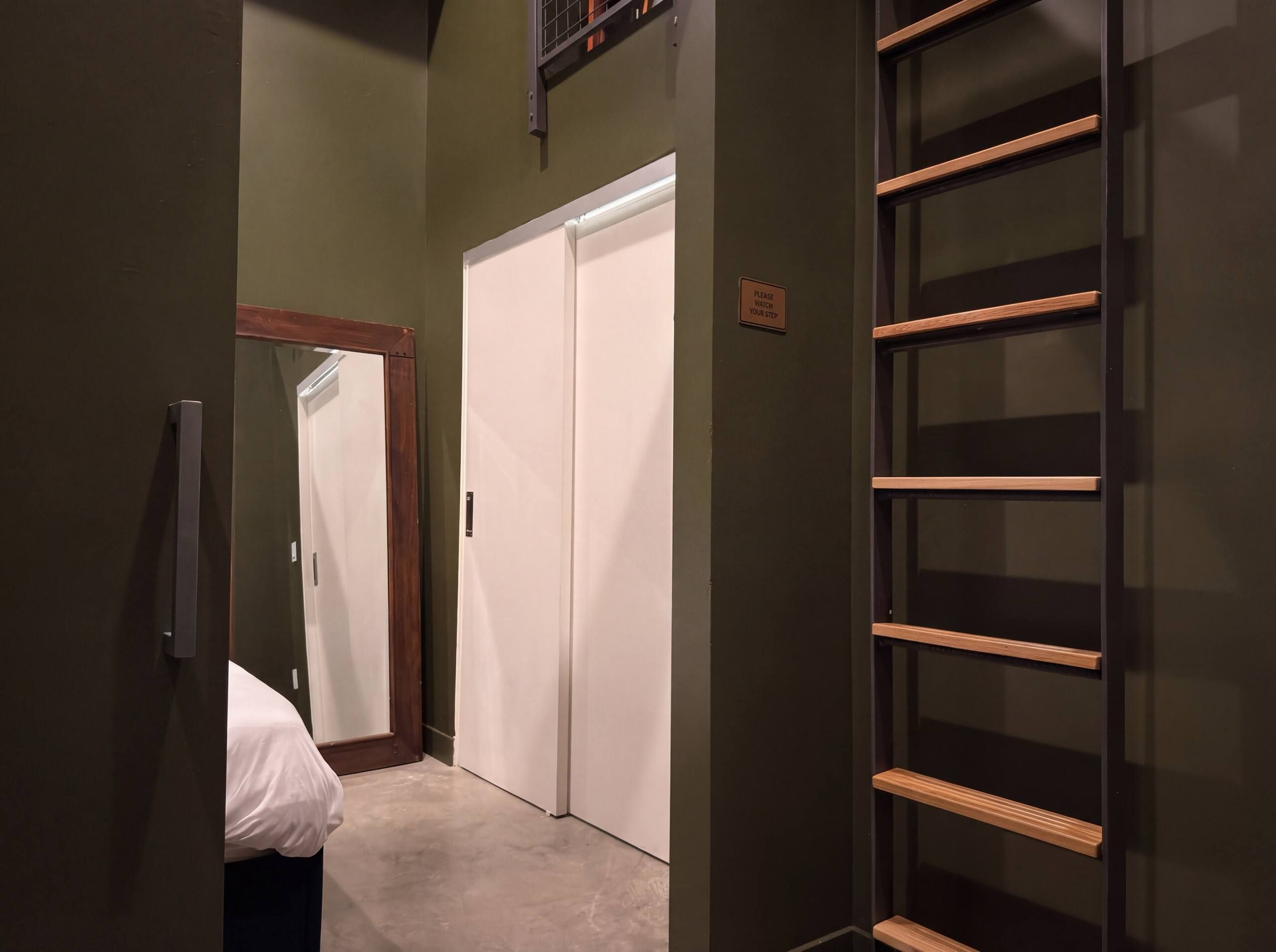 A hotel room with a bed, a wardrobe, and a built-in shelf unit.