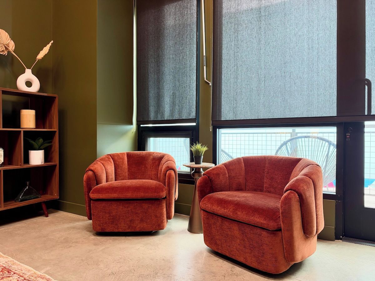 A room with two armchairs, a small table with a plant, and a bookshelf.