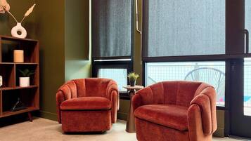 A room with two armchairs, a small table with a plant, and a bookshelf.