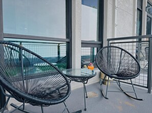 A balcony with two black wire mesh chairs and a small round table, overlooking a cityscape. - ⁂Pet Friendly⁂10min-Airport⁂AC⁂Gym⁂2Bed (Santa Ana)
