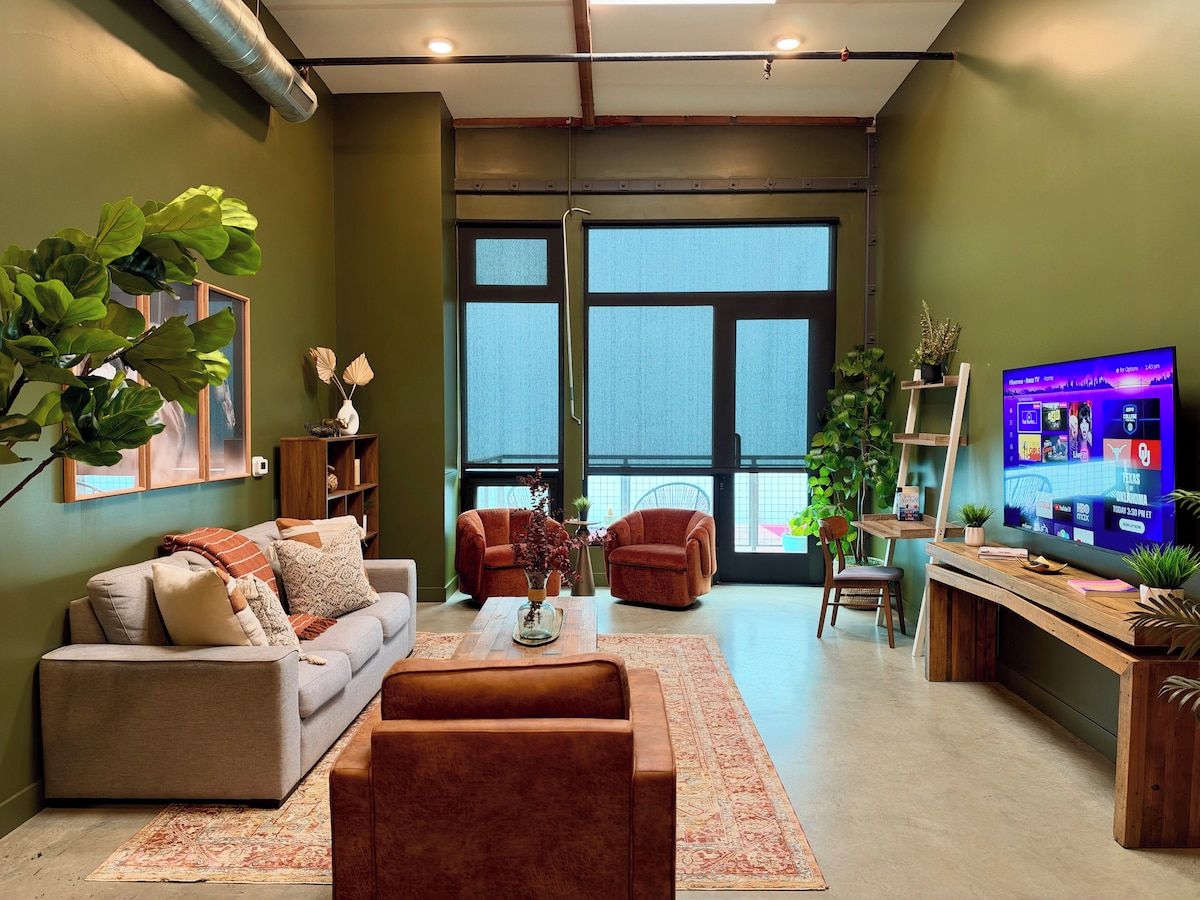 A modern living room with a sofa, armchairs, a coffee table, and a television.