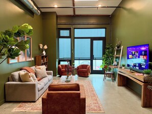 Een moderne woonkamer met een bank, fauteuils, een salontafel en een televisie.