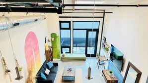 Een moderne woonkamer met een bank, twee gele stoelen, een salontafel en een groot raam met uitzicht.