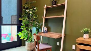 A room with a wooden chair, a bookshelf, and a potted plant.