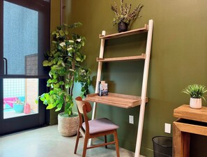 Een kamer met een houten stoel, een boekenplank en een plant in pot.