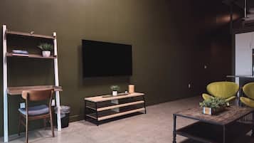 A modern living room with a flat-screen TV, wooden furniture, and a green accent wall.