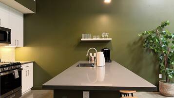 Una cucina con isola centrale, forno a microonde, piano cottura e macchina da caffè.