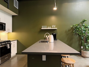 A kitchen with a central island, a microwave, a stove, and a coffee maker.