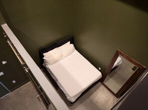 A single bed with white bedding in a room with green walls.