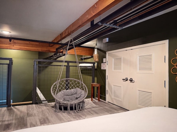 A room with a hanging chair, a wardrobe, and a door with a sign.
