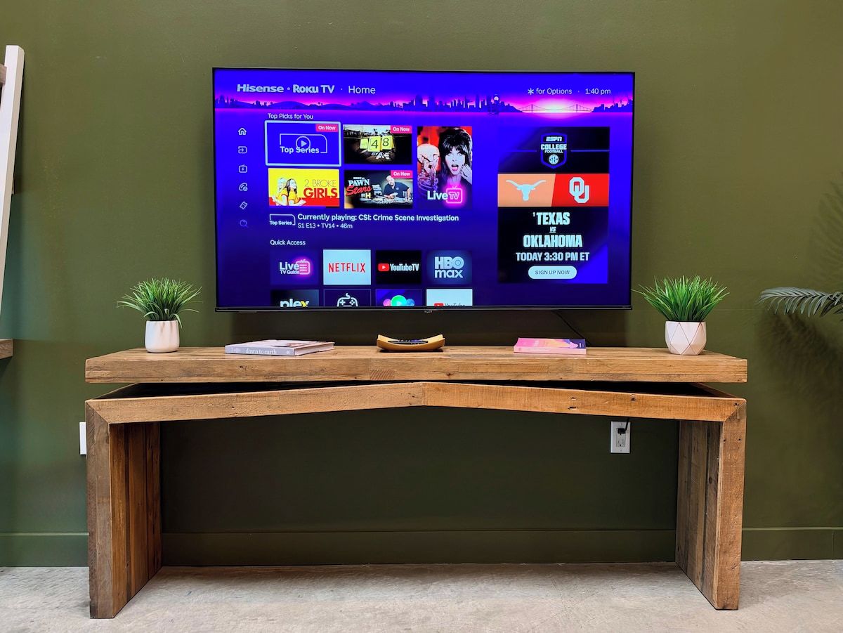 A flat-screen TV mounted on a wall with a wooden console table in front.