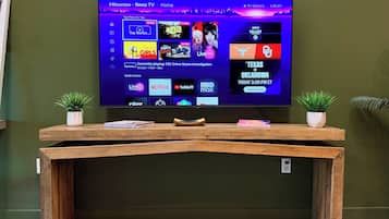 Una TV a schermo piatto montata a parete con un tavolino consolle in legno di fronte.