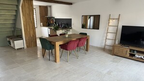 Ein zeitgemäßer Wohnbereich mit Essplatz, Fernseher und Treppe.