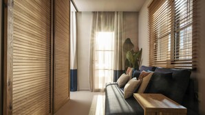 A modern living room with a sofa, wooden blinds, and a large plant. - Sewelo Suites (Zakynthos)