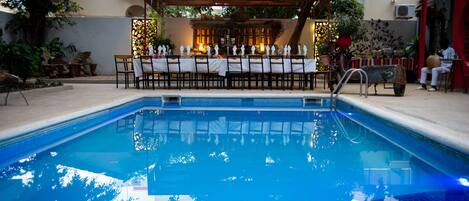 A swimming pool with a covered dining area in the background.