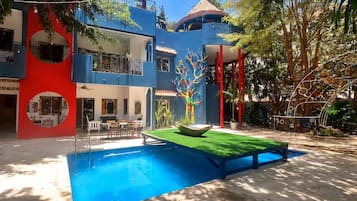A modern building with a pool, outdoor seating, and a colorful mural.