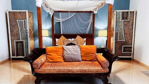 A bedroom with a canopy bed, a sofa, and two decorative panels.