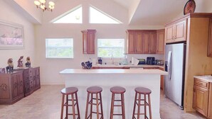 A kitchen with a central island, wooden cabinets, and a stainless steel refrigerator. - The Everglades House (Ochopee)