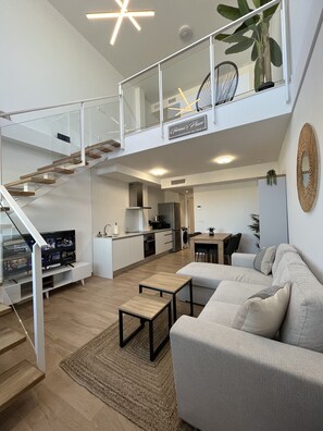 Un apartament modern amb saló, cuina i un balcó.