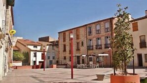 A quiet street with buildings, a red pole, and a tree. - Maison Pleine de Charme (Saint-Féliu-d'Avall)