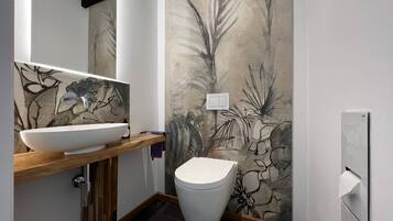 Ein modernes Badezimmer mit einem weißen Waschbecken, einer Toilette und einer Wand mit einem botanischen Wandbild.