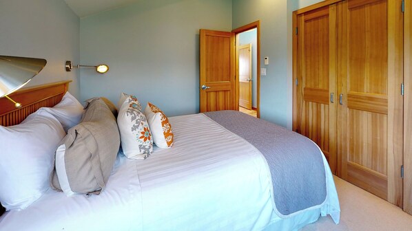 A bedroom with a bed, pillows, a bedside lamp, and wooden wardrobes.