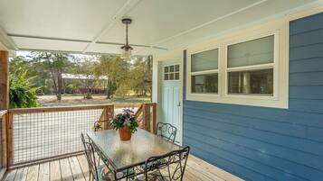 A covered porch with a table and chairs, a potted plant, and a view of the outdoors.