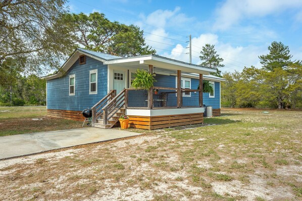 A single-story house with a front porch, a wooden staircase, and a small deck area.
