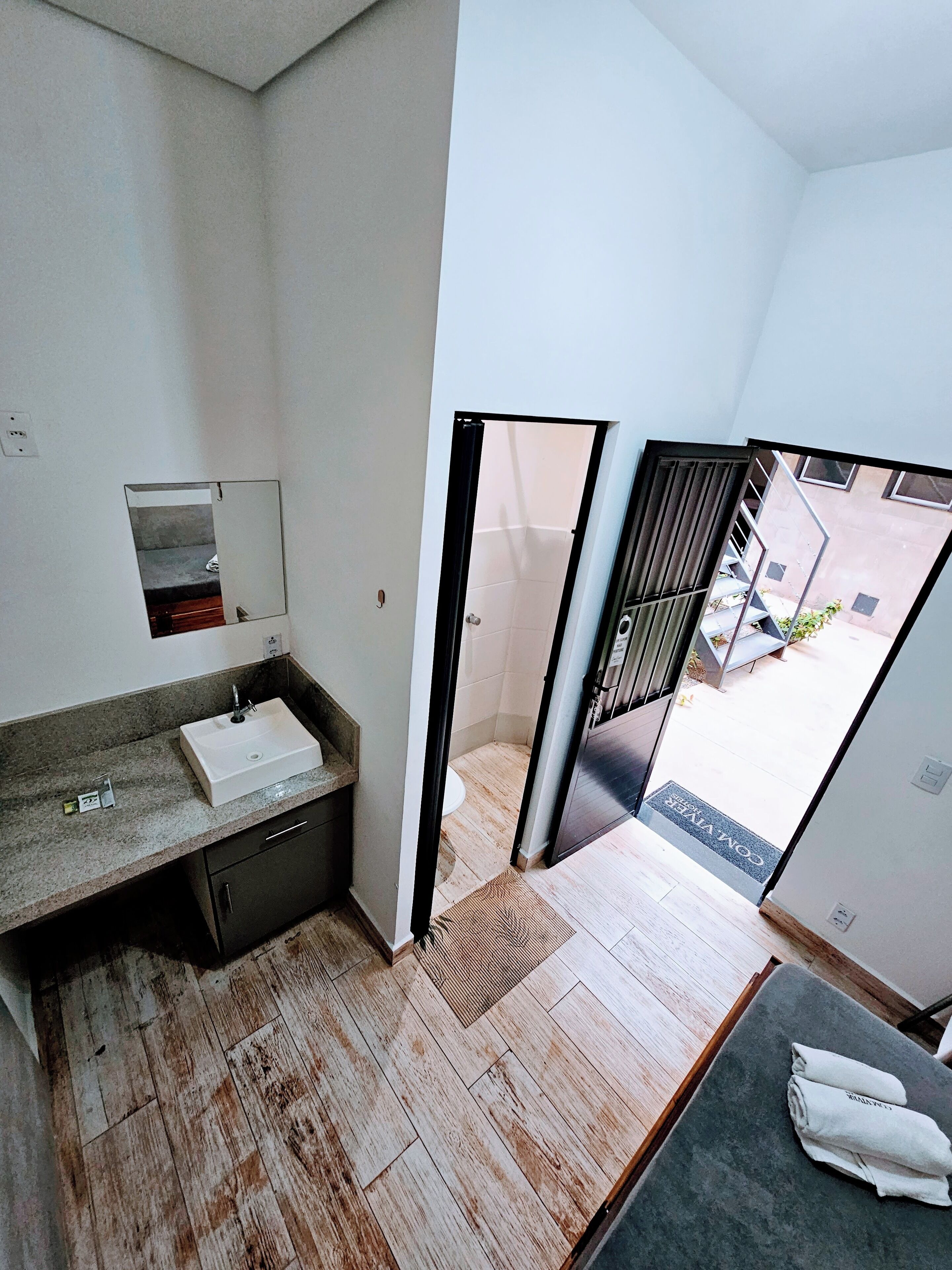 A modern bathroom with a sink, mirror, and wooden flooring.