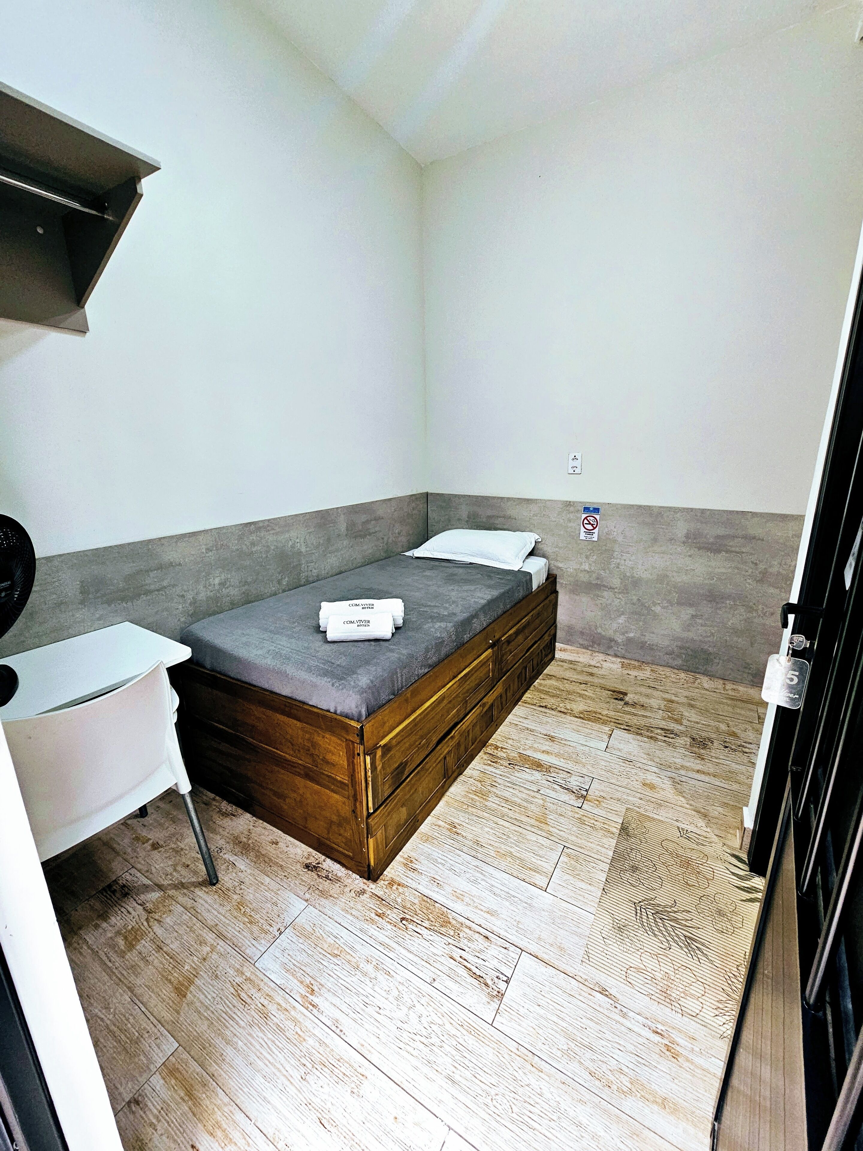 Una habitación pequeña y funcional con cama, escritorio y silla.
