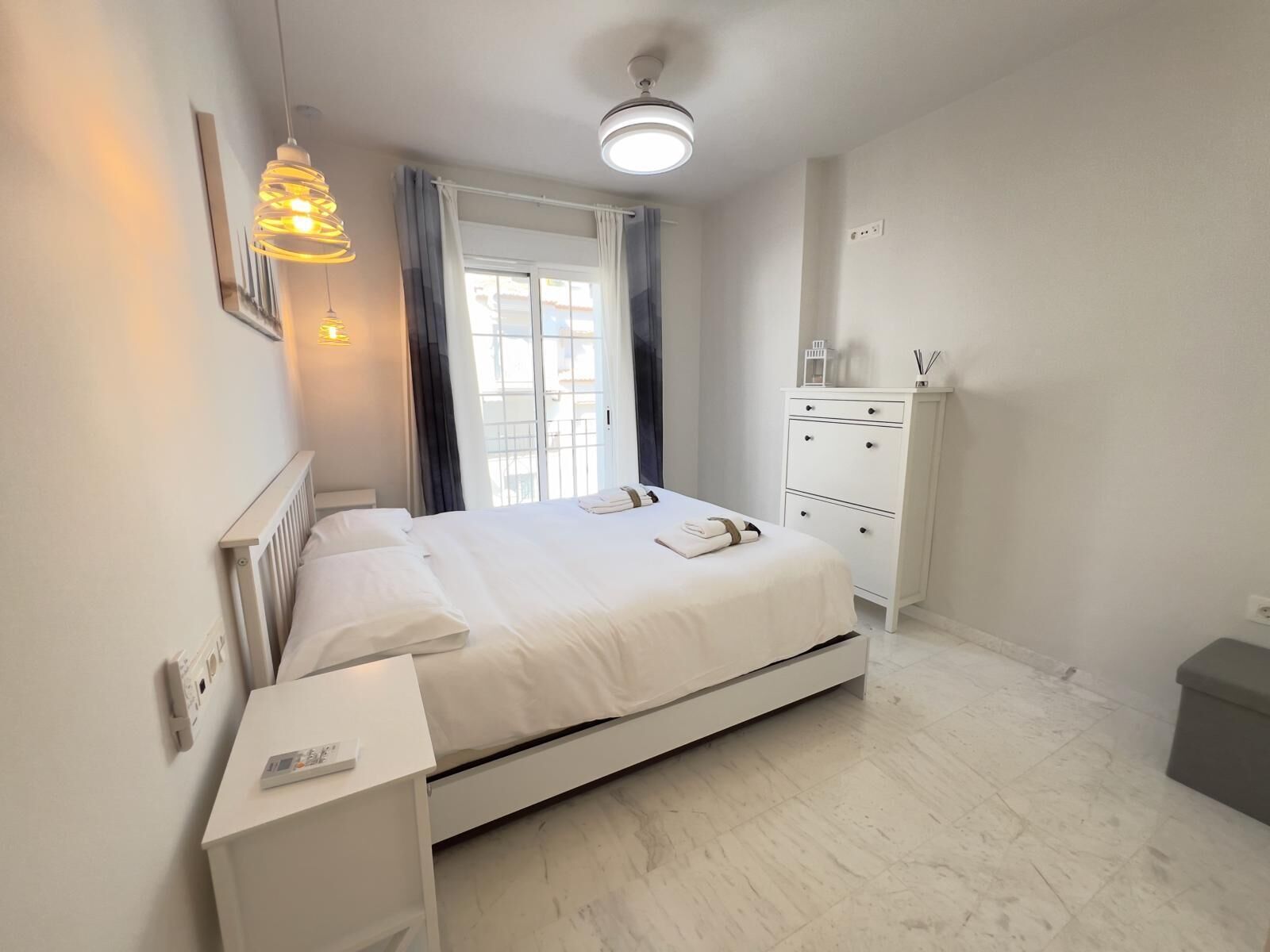 A modern bedroom with a bed, bedside tables, a wardrobe, and a ceiling light.