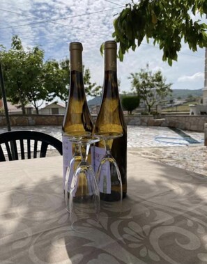 Two wine bottles and three wine glasses on a table with a patterned tablecloth.