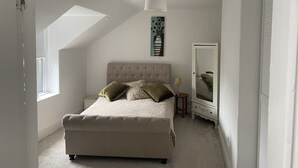 A bedroom with a large bed, a nightstand, a mirror, and a painting on the wall.