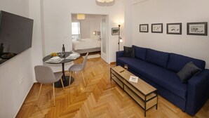 Ein modernes Wohnzimmer mit einem blauen Sofa, einem Esstisch mit Stühlen und einem Holztisch.