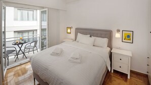 Ein Hotelzimmer mit Bett, Nachttischen, einem kleinen Tisch mit Stühlen und einem Balkon mit Tisch und Stühlen.