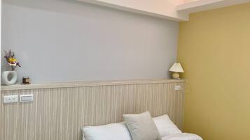 Habitación de hotel con una cama, una mesita de noche con lámpara y un enchufe en la pared.