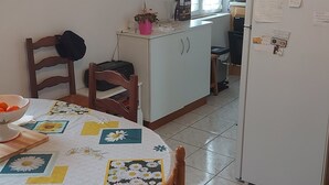 Une cuisine équipée d’une table à manger, de chaises, d’un réfrigérateur et d’une horloge murale.